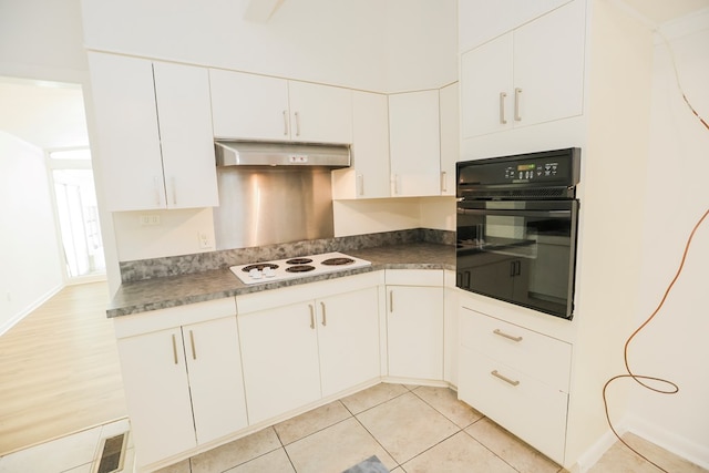 kitchen featuring under cabinet range hood, white electric cooktop, dark countertops, black oven, and white cabinets
