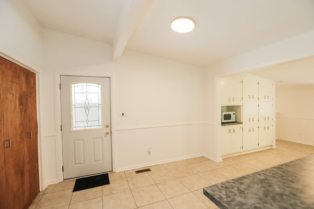 entrance foyer featuring baseboards, beamed ceiling, visible vents, and light tile patterned floors