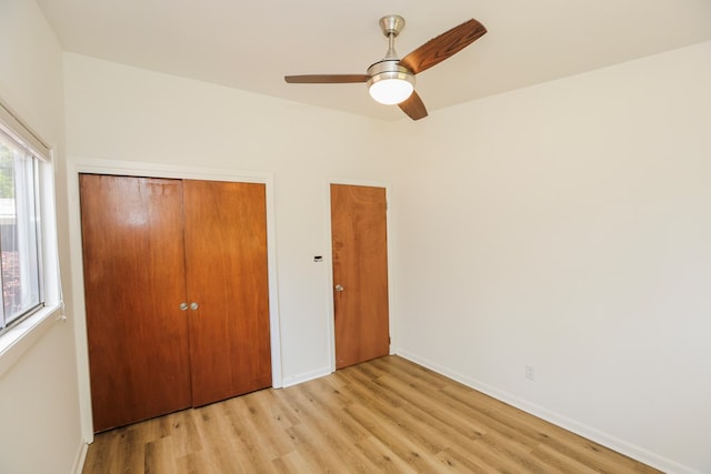unfurnished bedroom featuring baseboards, light wood-type flooring, a closet, and a ceiling fan