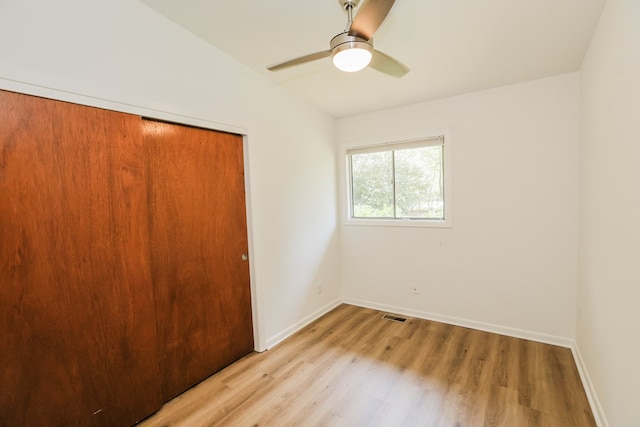 unfurnished bedroom with lofted ceiling, baseboards, visible vents, light wood-style flooring, and a closet