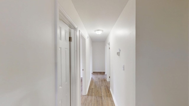 hallway with light wood-style flooring and baseboards