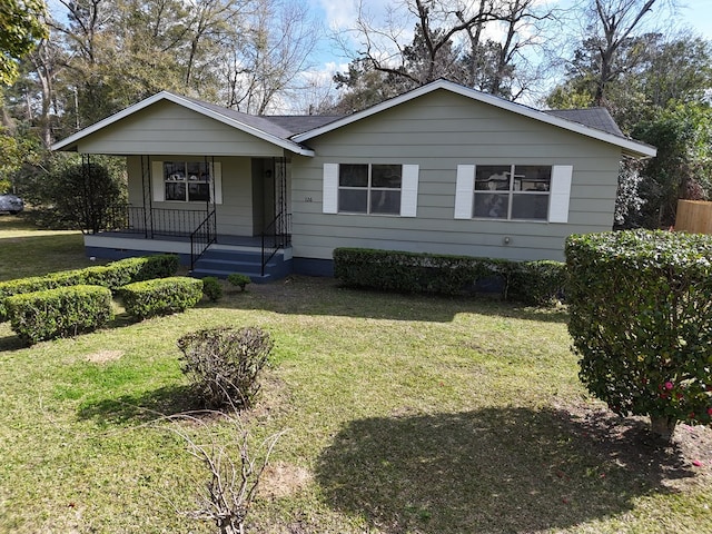 view of front of property featuring a porch, roof with shingles, and a front yard