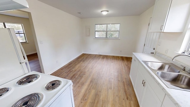 kitchen featuring white appliances, a sink, white cabinetry, light countertops, and light wood finished floors