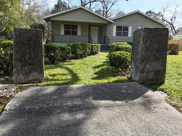 bungalow-style home with covered porch, fence, and a front yard