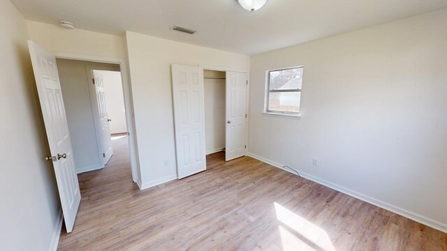 unfurnished bedroom with light wood-style flooring, a closet, visible vents, and baseboards