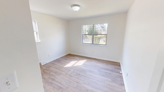 spare room with baseboards and wood finished floors