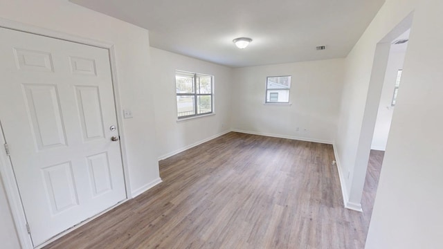 spare room featuring wood finished floors, visible vents, and baseboards