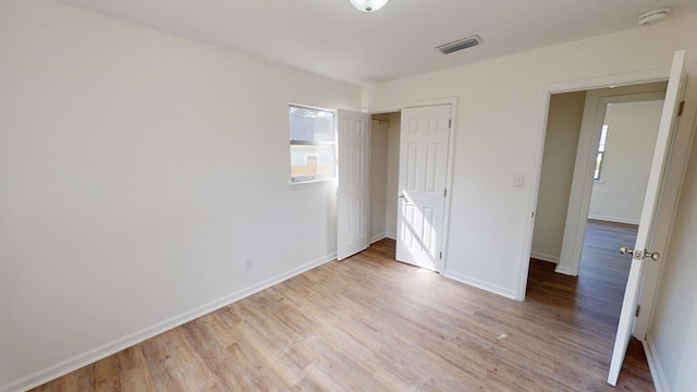 unfurnished bedroom with visible vents, a closet, light wood-style flooring, and baseboards