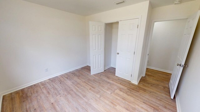 unfurnished bedroom featuring light wood-style floors, a closet, visible vents, and baseboards