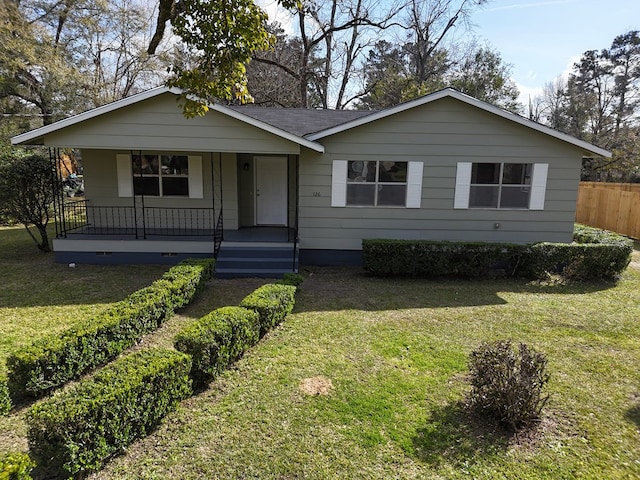 ranch-style house featuring a front lawn, roof with shingles, a porch, and fence