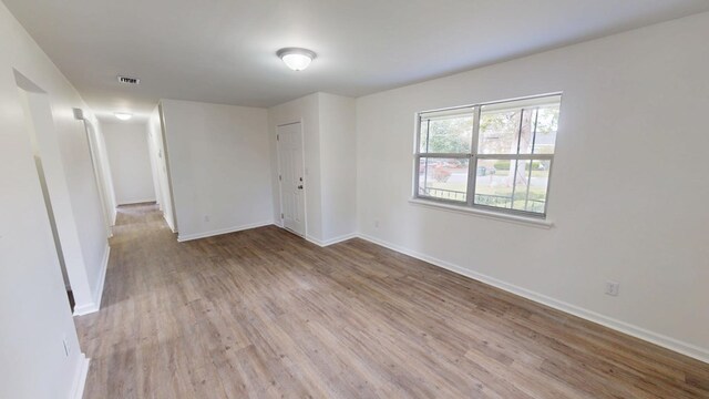 spare room featuring light wood-style floors, baseboards, and visible vents