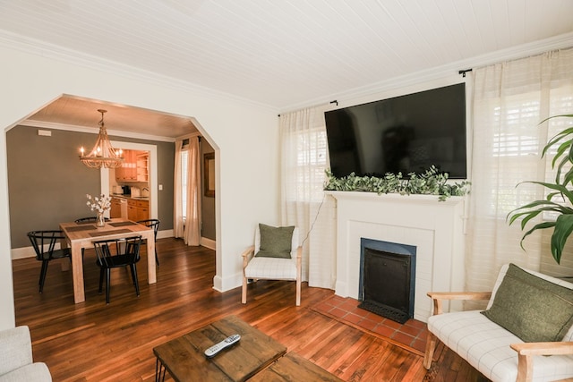 living area featuring baseboards, arched walkways, wood finished floors, and crown molding