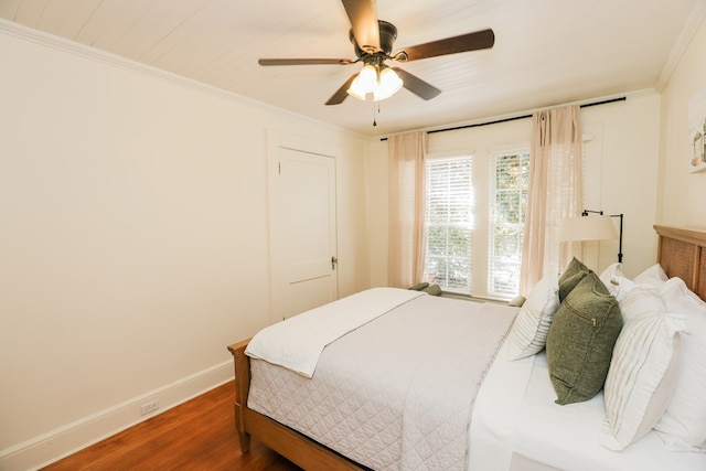 bedroom with ceiling fan, crown molding, baseboards, and wood finished floors