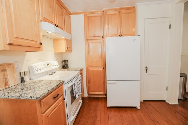 kitchen featuring light brown cabinetry, hardwood / wood-style flooring, under cabinet range hood, light stone counters, and white appliances