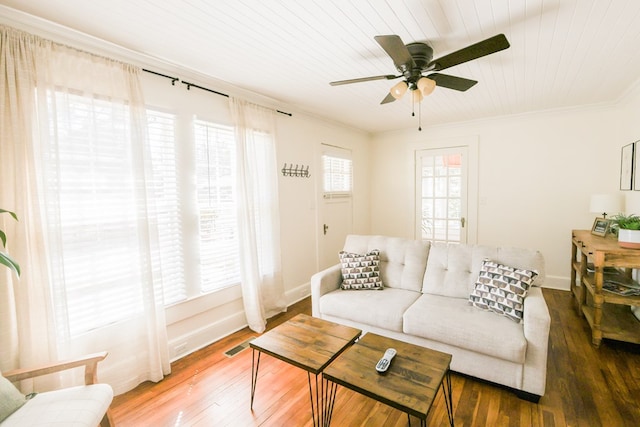 living room with baseboards, wood finished floors, visible vents, and ornamental molding