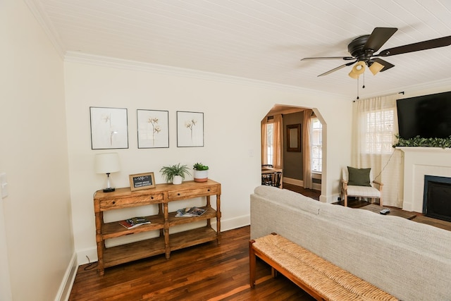 bedroom featuring a fireplace with flush hearth, ornamental molding, arched walkways, baseboards, and dark wood-style flooring