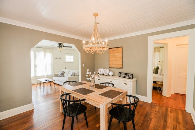 dining room with dark wood-style floors, arched walkways, baseboards, and ornamental molding