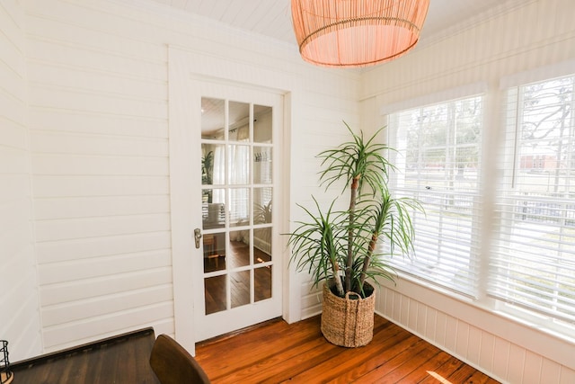 interior space with a healthy amount of sunlight, crown molding, and wood finished floors