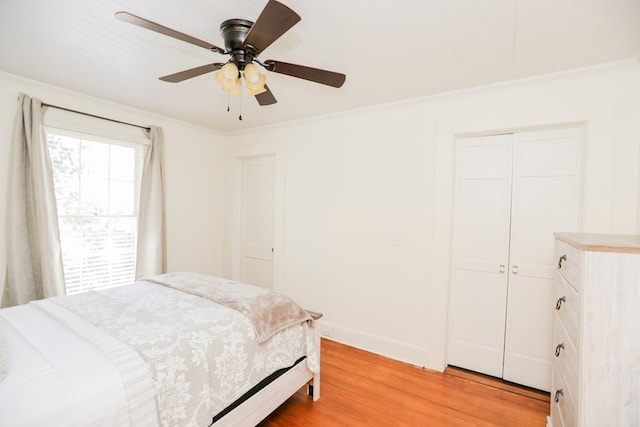 bedroom featuring light wood finished floors, a ceiling fan, a closet, and ornamental molding