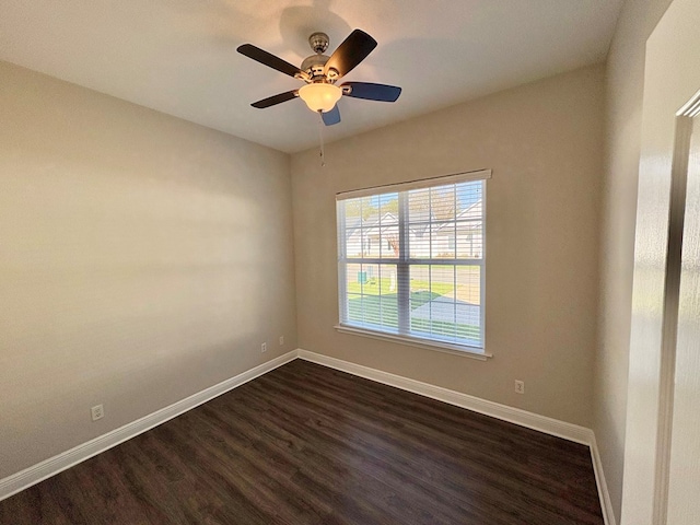 spare room featuring a ceiling fan, dark wood-type flooring, and baseboards