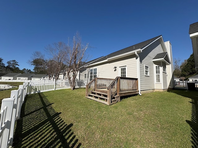 rear view of property with a yard, a chimney, a wooden deck, and a fenced backyard