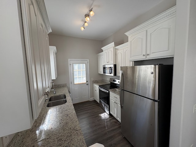 kitchen with light stone countertops, appliances with stainless steel finishes, dark wood-style floors, white cabinetry, and a sink