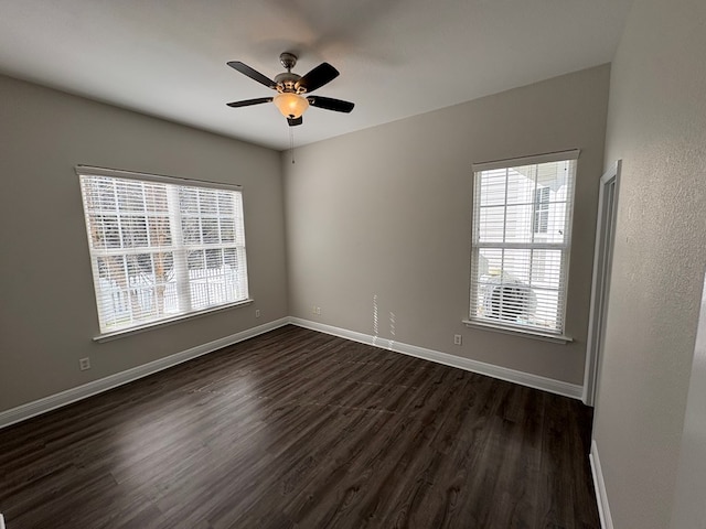 empty room with baseboards, dark wood-style floors, and a ceiling fan