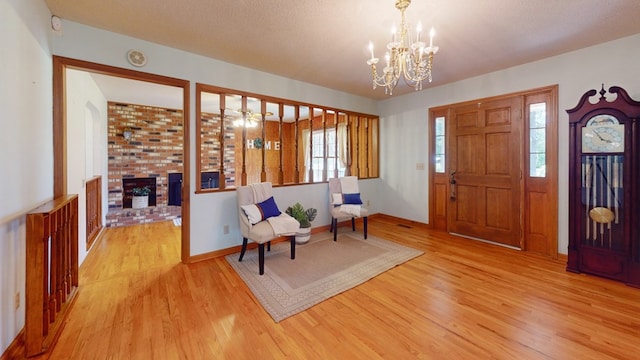 foyer entrance with wood finished floors, a chandelier, a fireplace, and baseboards