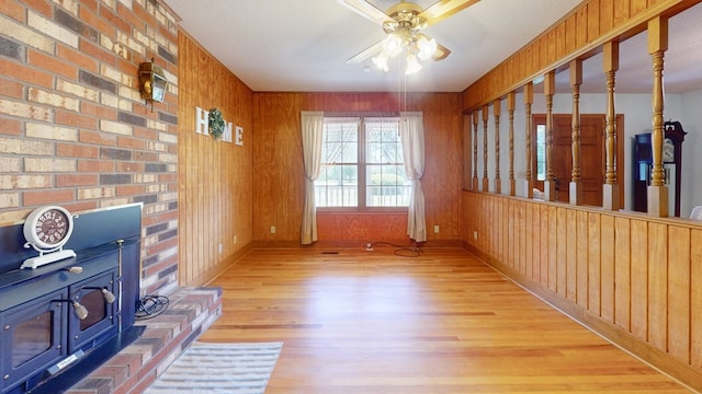living room with a ceiling fan, wood finished floors, baseboards, and wooden walls
