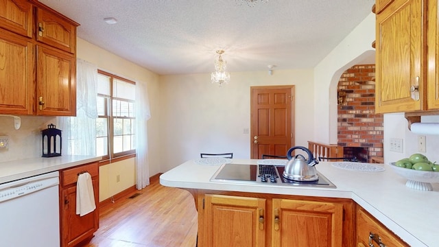 kitchen featuring white dishwasher, black electric stovetop, a peninsula, light countertops, and light wood-style flooring