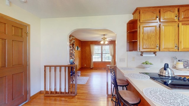 kitchen featuring light wood-style floors, arched walkways, light countertops, and ceiling fan