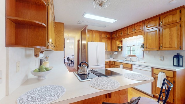 kitchen featuring open shelves, white appliances, a peninsula, a sink, and light countertops