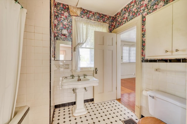 902 SE 2nd St, Moultrie, GA 31776 - full bathroom featuring wallpapered walls, toilet, plenty of natural light, tile walls, and tile patterned flooring