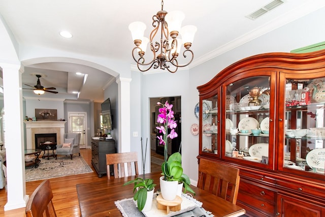 110 Quail Rdg, Ochlocknee, GA 31773 - dining room featuring ceiling fan, arched walkways, ornamental molding, light wood-type flooring, and a tiled fireplace