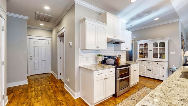 kitchen with visible vents, under cabinet range hood, white cabinets, range with two ovens, and decorative backsplash