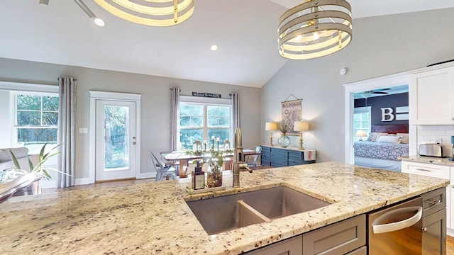 kitchen featuring a sink, light stone counters, white cabinets, and vaulted ceiling