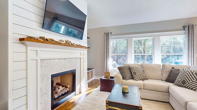 living area with a wealth of natural light, wood finished floors, and a tile fireplace