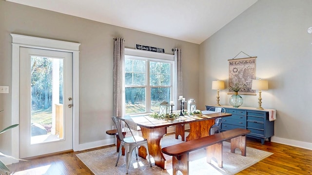 dining space with baseboards, wood finished floors, and vaulted ceiling