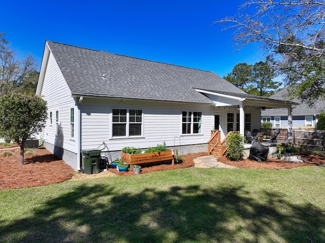 back of house with a lawn, a shingled roof, and fence