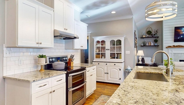 kitchen featuring range with two ovens, a sink, white cabinets, under cabinet range hood, and light wood-type flooring