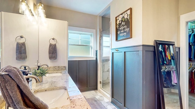 full bathroom with a walk in closet, a shower stall, wainscoting, and a sink