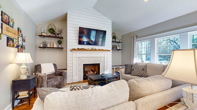 living area featuring lofted ceiling, wood finished floors, baseboards, and a large fireplace