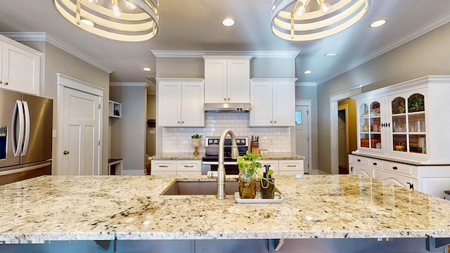 kitchen with under cabinet range hood, stainless steel appliances, decorative backsplash, and crown molding