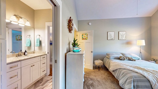 bedroom featuring a sink, light carpet, and ensuite bathroom