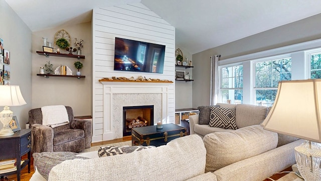 living area with lofted ceiling, wood finished floors, and a large fireplace