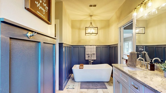 bathroom with vanity, visible vents, a freestanding bath, wainscoting, and a chandelier