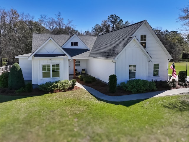 modern farmhouse featuring board and batten siding, a shingled roof, and a front lawn