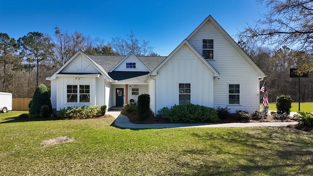 view of front of property with board and batten siding, a front lawn, and a shingled roof