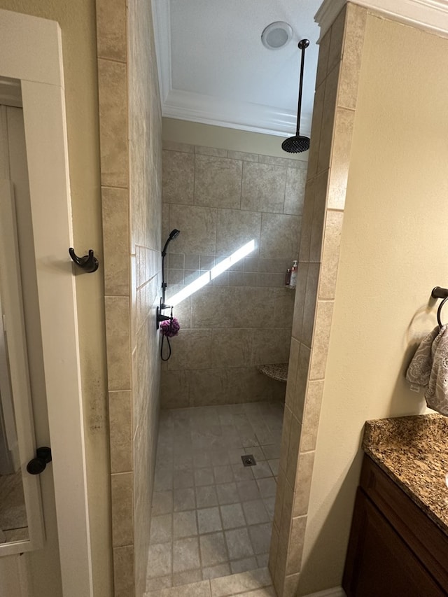 bathroom with vanity, a tile shower, and crown molding