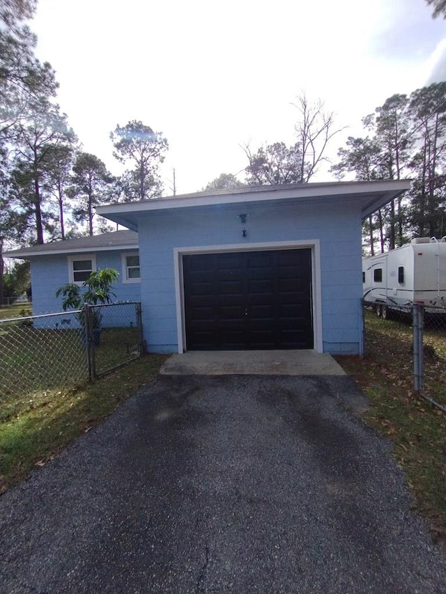 garage featuring fence and aphalt driveway